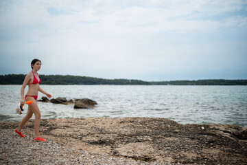 Young woman walking rocky beach carrying snorkel gear © Zoran Jesic