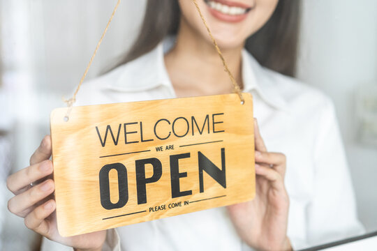 Smiling young asian business owner, employee retail,coffee shop woman,girl turning,setting sign board to open for welcome customer, reopen store after close lockdown quarantine in covid.Label concept.