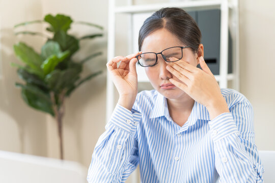 Eye problem concept, fatigue asian young woman tired eyes, irritated rubbing nose, relief vision pain after work on laptop computer, eye strain, hand holding glasses, suffer migraine, bad blurry.