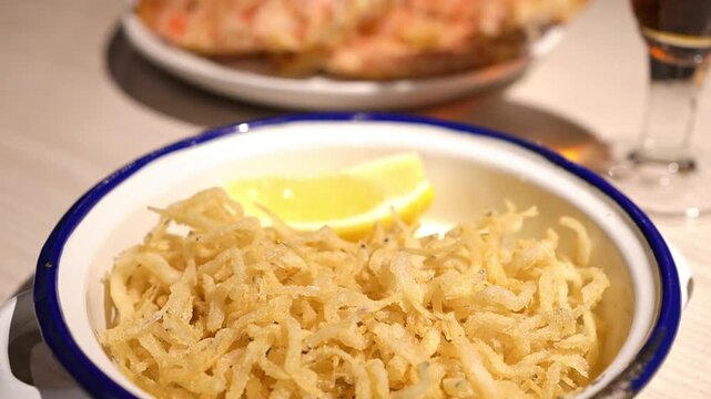 Crispy fried whitebait chanquetes with pan con tomate in background, traditional spanish tapas
