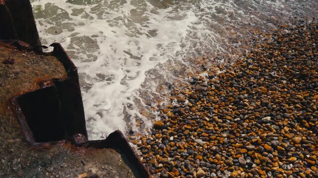Top View of Waves Breaking Over Pebbles on the Shore