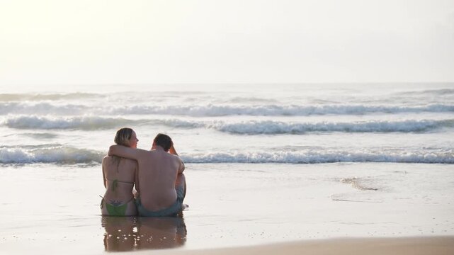 Happy couple embracing and kissing in shallow waves, enjoy peaceful summer holiday by sea. Romantic travel, beach lifestyle, love, happiness and unforgettable vacation memories concept