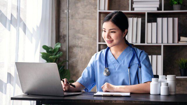 Asian Woman Doctor Using Laptop for Online Consultation in Clinic Medical Professional Healthcare Technology