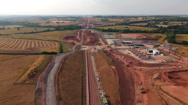 Aerial view of HS2 rail construction site featuring extensive earthworks and heavy machinery across the rural landscape in Southam, England, United Kingdom.