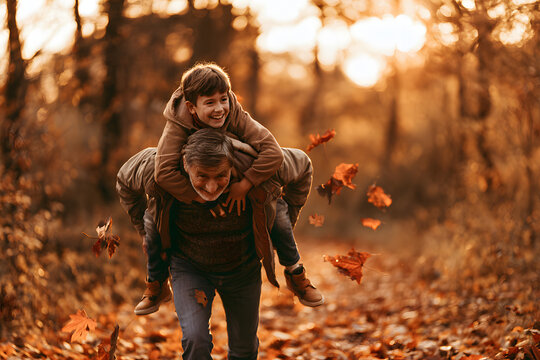 The grandson rode piggyback with his grandfather during autumn.