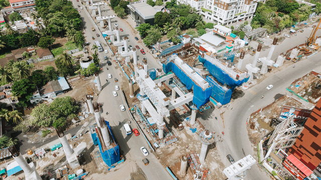 Metro rail construction over a city road with piers and blue barriers below