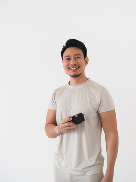 Smiling Asian Man Holding a Compact Digital Camera Against a Clean White Background