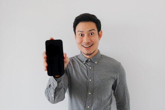 Excited Asian Man Holding Up Blank Smartphone Screen for Advertisement or App Display