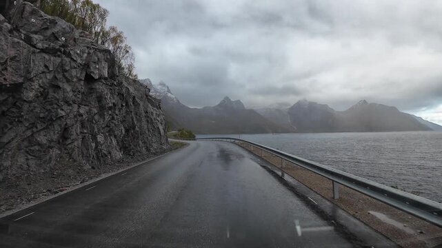 Motorhome journey along a wet coastal road with fjords and mountains on the island of Senja