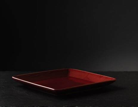 Deep red square plate rests on dark surface
