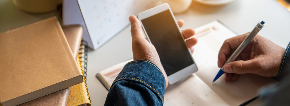 Calendar reminder event concept.Man hand planner or organizer writing in diary and 2026 Calendar page.Student holding smartphone and planning appointment.Male noted and count Down schedule day in book