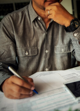Budget and Tax planning concept. Accountant hand using calculator and review tax forms. Represents personal finance, tax preparation, budgeting, and season to pay tax-vertical image