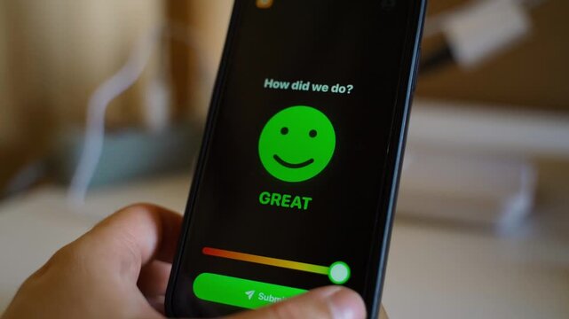 Hand holding smartphone showing customer feedback survey with green smiley on dark screen 