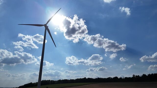 &eacute;olienne en fonction avec le soleil &agrave; l'arri&egrave;re en contre-jour, ciel bleu avec des nuages cumulus