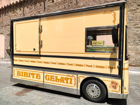 Rome, Italy - May 17, 2026: Gelato food truck with yellow exterior and signage displaying "Bibite Gelati" parked on a cobblestone street in an urban setting