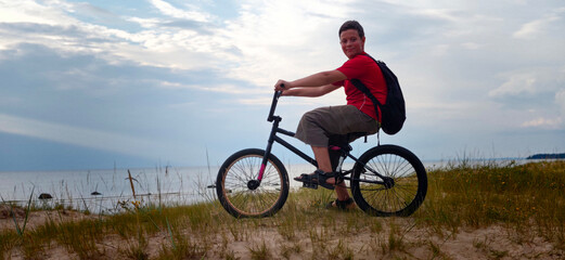 Fototapeta premium Boy rides bike on sunny path while another rider performs tricks on BMX