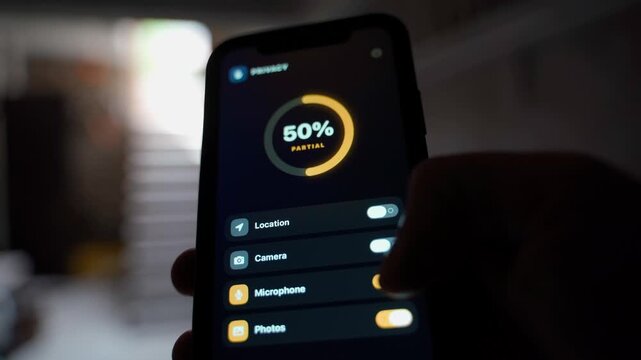 Hand holding smartphone showing privacy settings with permission toggles close-up 