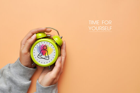 Hands holding alarm clock with Time for Yourself message, self care concept