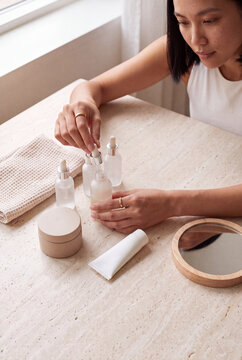 Minimal skincare flatlay with serums creams and mirror on marble table with woman preparing beauty routine for selfcare