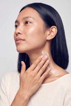 Woman applying moisturizer cream to neck and jawline for a skincare routine and beauty product background or banner design