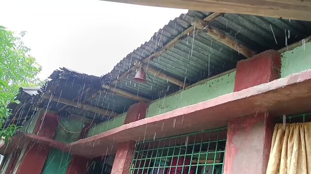 Heavy rain dripping from corrugated metal roof of house during monsoon season raindrops falling from eaves in rural rainy weather