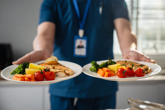 Male Caregiver Presenting Two Healthy Meals with Grilled Salmon, Broccoli, Carrots, Potatoes and Roasted Tomatoes in a Bright Contemporary Home Kitchen