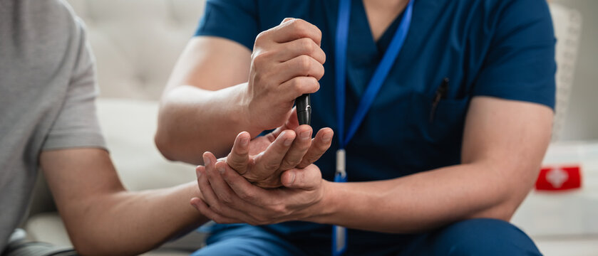 Senior Healthcare Nurse Performing a Finger Prick Blood Glucose Test for an Asian Elderly Man during a Home Health Checkup in a Close-Up View