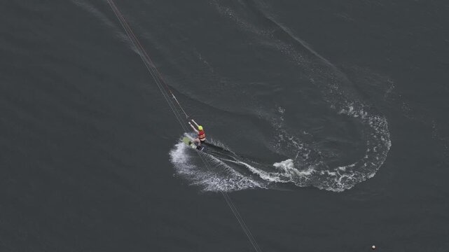 Aerial view of a person wakeboarding on dark water, creating a wake behind the board in Vilnius, Vilnius County, Lithuania.