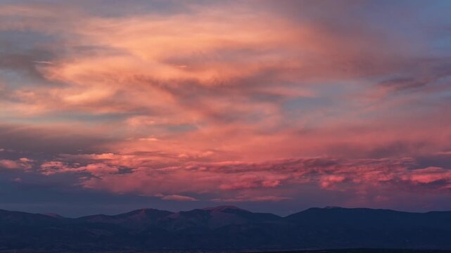 Aerial view of sunset over Mt Baldy in the Sangre de Cristo Range with dramatic purple and pink clouds in Los Alamos, NM, United States.