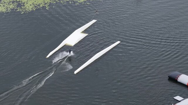 Aerial view of a wakeboarder performing tricks on a cable park course with ramps in the water in Vilnius, Vilnius County, Lithuania.
