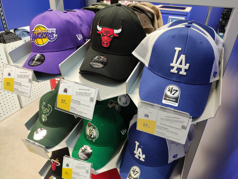 Rome, Italy - July 20, 2026: Collection of sports caps displayed on a shelf featuring Los Angeles Lakers, Chicago Bulls, and Los Angeles Dodgers logos in a retail store