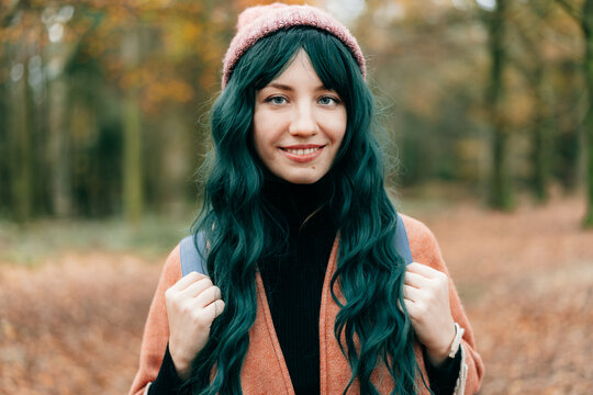 Young Woman wrapped in warm Shawl Poncho enjoying autumn walk in forest with fall yellow leaves. Travel lifestyle. Feeling harmony, reunion with nature. Relaxing, mental recovery. Local travel.