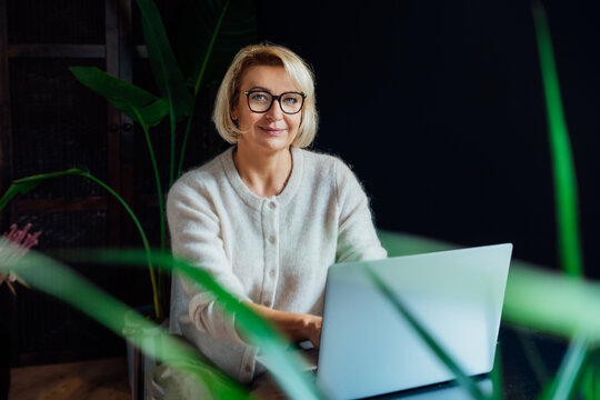 Portrait of stylish 50's confident mature businesswoman, middle aged company ceo director, experienced senior female professional, business coach working on laptop in office. Female leader.