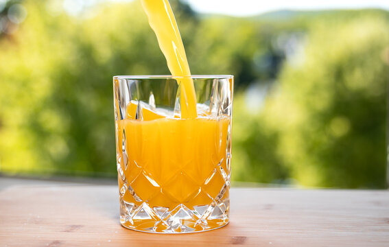 Close-up of freshly squeezed orange juice flowing into a glass, the fruit contains fructose. Refreshing soft drink in the summer. Refreshment, vitamin C, healthy lifestyle, non-alcoholic drink.