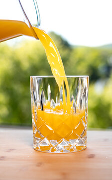 Freshly squeezed orange juice is poured into a glass, fruit contains fructose. Popular, refreshing soft drink in the summer. Refreshment, vitamin C, healthy lifestyle, non-alcoholic drink.