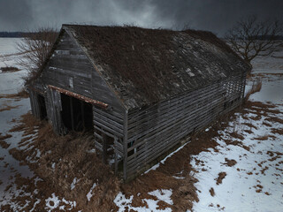 Weathered Wooden Barn in Snowy Landscape with Moss‑Covered Roof, Structural Decay, and Leafless Trees Under Dark Sky © Jason