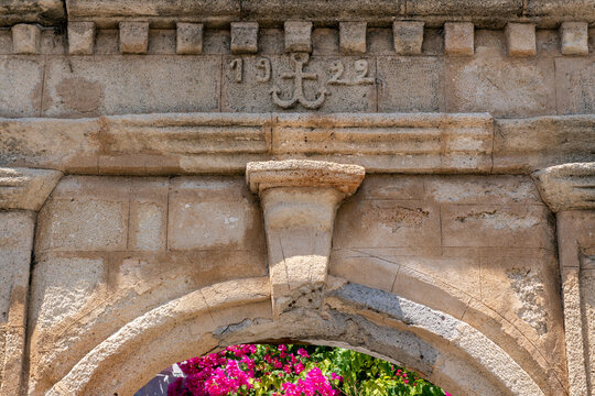 Historic arch with year 1922 and floral display in the village of Lindos