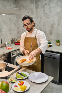 Chef cooking salmon in modern kitchen preparing healthy meal