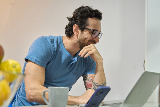 Man laughing while working on laptop at home