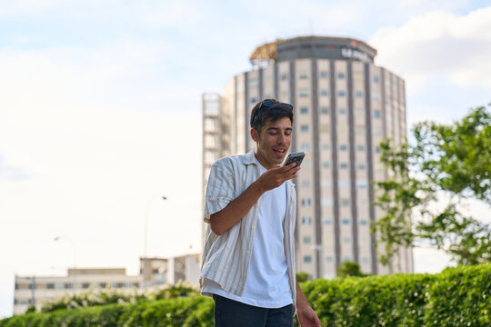 Young man using smartphone walking in urban setting