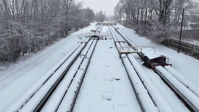 Oil pipeline scene showcasing extensive network of pipes on snowy landscape at cold winter. Aerial shot revealing infrastructure and natural surroundings emphasizing energy transport. Industrial pipes