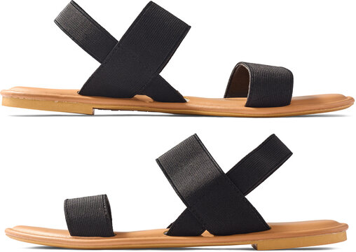 pair of black flat ladies sandals isolated white background, elastic criss cross straps and tan brown soles summer footwear, close-up side view