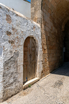 Stone archway with a wooden door near a narrow street in Lindos