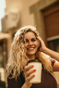 Happy woman enjoying music and coffee outdoors