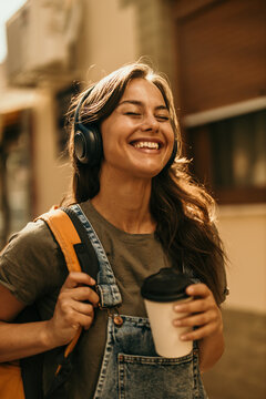 Young woman enjoying music outdoors smiling broadly