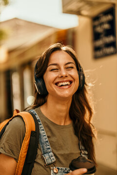 Young woman enjoying music and coffee on city street