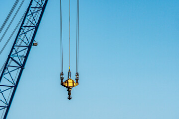 Naklejka premium Yellow crane hook with cables against clear blue sky