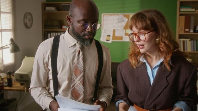 African American man and Caucasian woman discussing documents in retro office. Footage is suitable for vintage corporate training or diverse business history campaigns