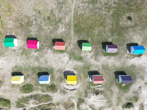 Aerial view of the iconic colorful beach huts lined up on the sandy dunes in Gouville-sur-Mer, Normandy, France.