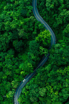 Aerial forest road with car creating abstract background for electric vehicle, ESG, sustainability and green investment business concepts.
